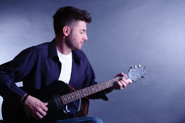 Young musician playing guitar on gray background - Foto, Imagem