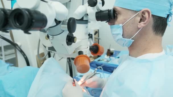 Χειρουργός που εξετάζει το μικροσκόπιο στο μάτι μιας γυναίκας ασθενούς στο χειρουργείο. Γιατρός που χρησιμοποιεί μικροσκόπιο κατά τη διάρκεια χειρουργικής επέμβασης στα μάτια, θεραπεία καταρράκτη και διόρθωση διόπτερου. - Πλάνα, βίντεο