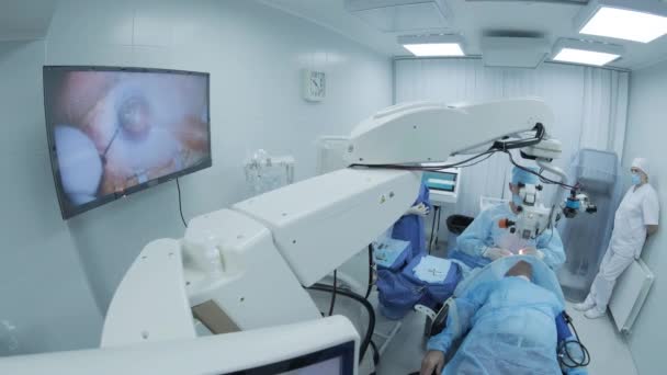 Chirurg kijkt naar de microscoop in het oog van een vrouwelijke patiënt in de operatiekamer. Arts met behulp van microscoop tijdens oogchirurgie, behandeling van cataract en diopter correctie. - Video