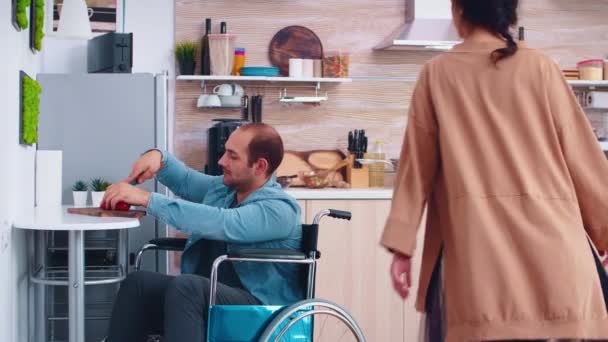 Mozgássérült férfi tolószékben harangbors darabolása a konyhában - Felvétel, videó