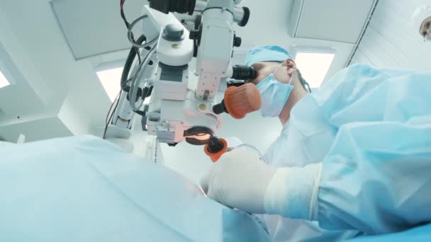 Chirurgien regardant dans le microscope à l'oeil d'une patiente dans la salle d'opération. Médecin utilisant le microscope pendant le processus de chirurgie oculaire, le traitement de la cataracte et la correction du dioptre. - Séquence, vidéo