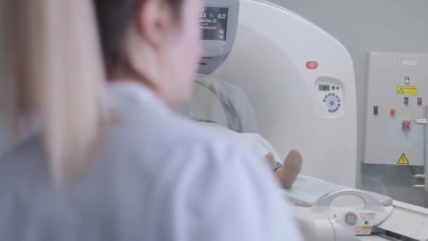 Kobieta leżąca na tomografii komputerowej lub rezonansie magnetycznym podczas obrazowania jej ciała, zapala promienie podczerwone i pacjentka przechodzi przez krąg, żuraw strzela od dołu do góry, wnętrze pokoju, aktywna scena. - Materiał filmowy, wideo