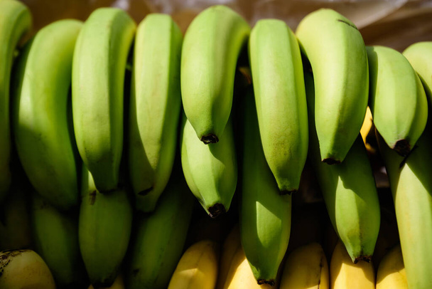 Group of fresh green bananas available for sale at a street food market, natural background, soft focus - Photo, Image