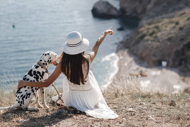 Woman with a dog dalmatian. Girl and her friend dog on the blue sea background - Фото, изображение