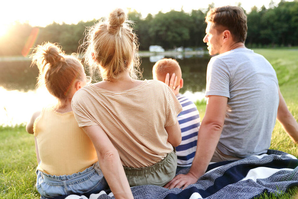 Сім'я спостерігає за заходом сонця біля озера
 - Фото, зображення