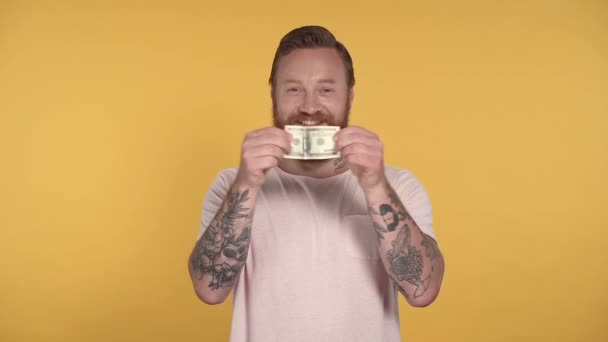 Portrait of smiling bearded man tearing dollar note. Slowmotion. - Кадры, видео