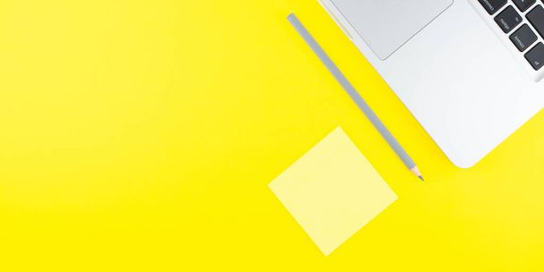 Laptop, pencil and notepad stick on yellow background. Flat lay. Copy space. Workplace in the office.  - 写真・画像