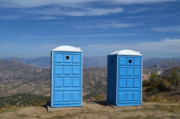 Dağın tepesinde iki portatif tuvalet turistler için, teleferiğin yanında. Beldersay Dağları, Özbekistan. - Fotoğraf, Görsel