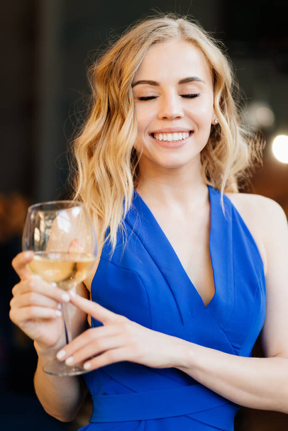girl in blue dress standing with glass of wine. - Фото, изображение