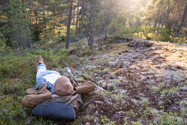 L'uomo giace sull'erba, riposando in mezzo alla foresta rilassante - Foto, immagini