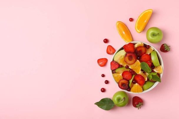 Bowl of fresh fruit salad on pink background, top view - Photo, Image