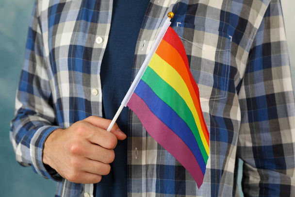 Mies pitää LGBT-lippua sinistä taustaa vasten - Valokuva, kuva