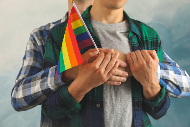 Schwules Paar mit LGBT-Flagge umarmt sich drinnen - Foto, Bild