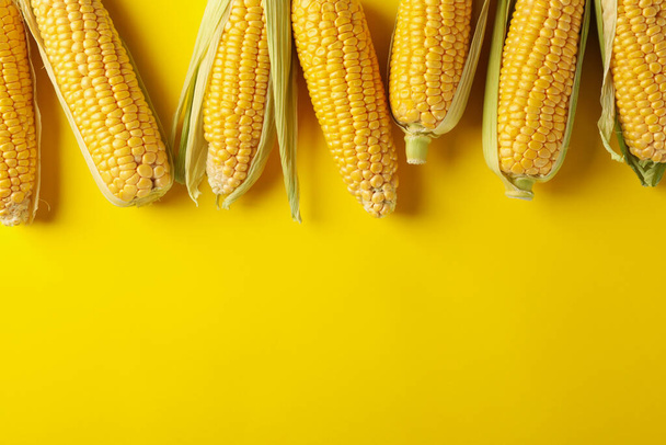 Frischer roher Mais auf gelbem Hintergrund, Draufsicht - Foto, Bild