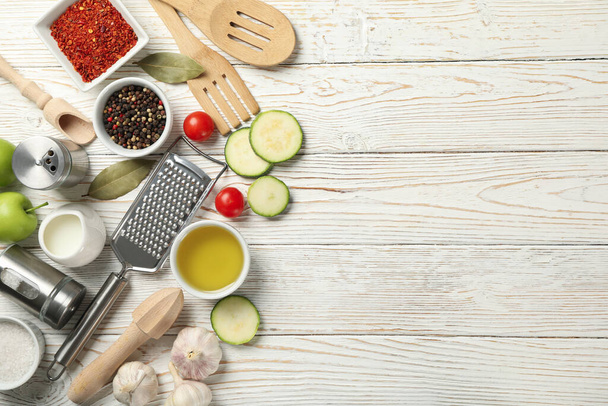Состав с кухонными принадлежностями и ингредиентами для приготовления пищи на белом деревянном фоне, вид сверху - Фото, изображение