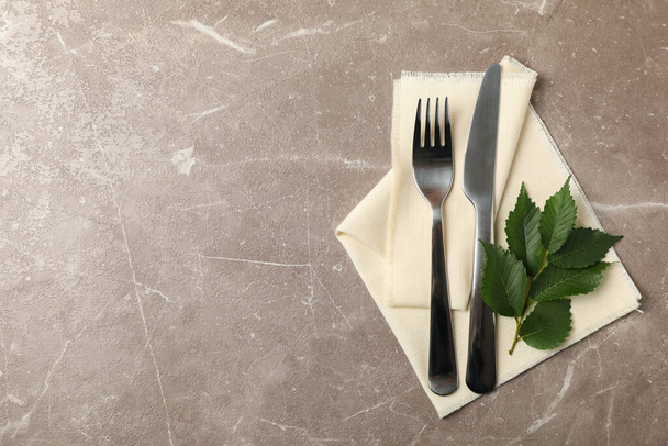 Napkin, cutlery and leaves on gray background, space for text - Photo, Image
