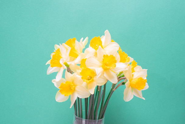 kytice žlutých narcisů květiny na zeleném barevném papíře pozadí. - Fotografie, Obrázek