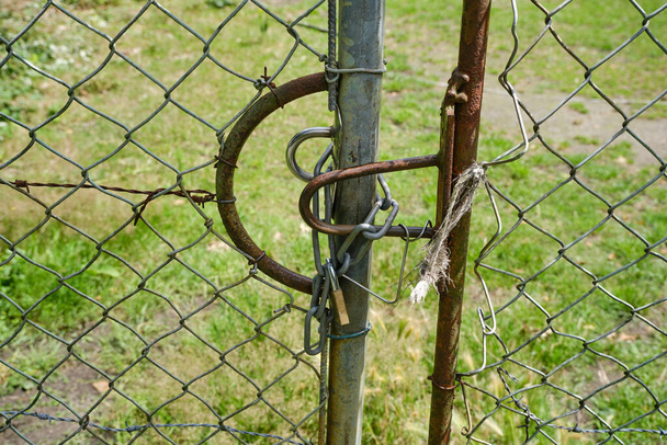 Grande recinto con rete metallica e filo spinato una catena e un lucchetto. Prateria, prato cantiere sfondo - Foto, immagini