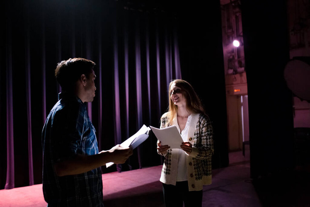 Rehearsal at theatre. Man explain to student actress how to play on the stage on the new performance for public. Dark hall at background. - Foto, imagen