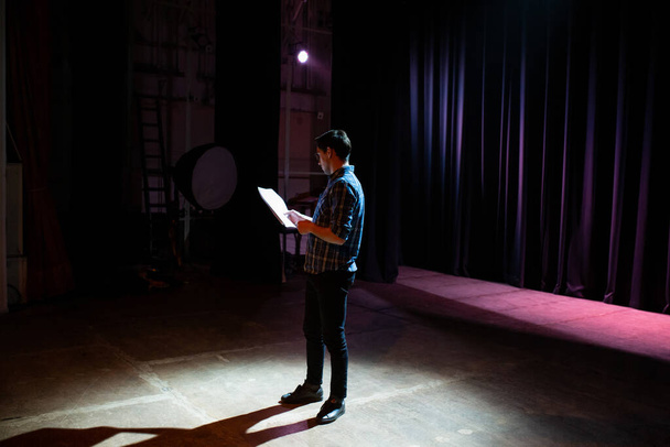 Medium shot of actors and actresses rehearsing a scene in a theater. Medium shot of an actor performing a monologue in a theater while holding his script - Foto, afbeelding