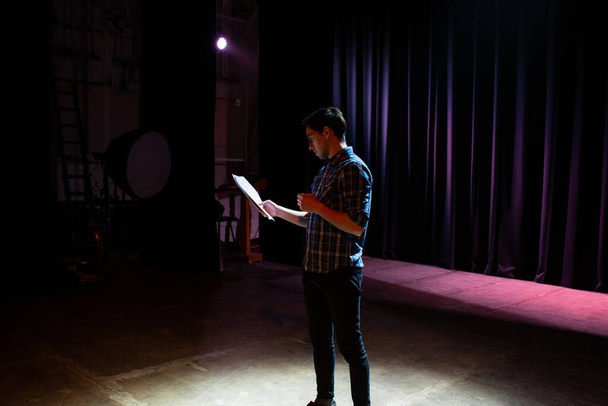 Medium shot of actors and actresses rehearsing a scene in a theater. Medium shot of an actor performing a monologue in a theater while holding his script - Foto, Imagen