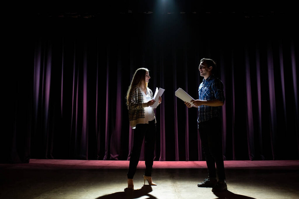 Rehearsal at theatre. Man explain to student actress how to play on the stage on the new performance for public. Dark hall at background. - Φωτογραφία, εικόνα