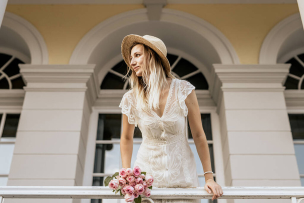 Portrait of blond smiling woman in white dress. Beautiful girl stay on balcony at home - Photo, Image