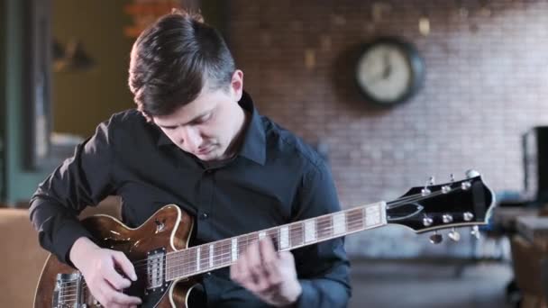 handsome man in black shirt playing on guitar beautiful blues composition in cafe. Retro studio, brick interior. Jazz, Blues, Funk. Medium long shot - Πλάνα, βίντεο