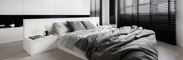 Panorama of stylish bedroom designed in white with big windows with black blinds - Photo, image