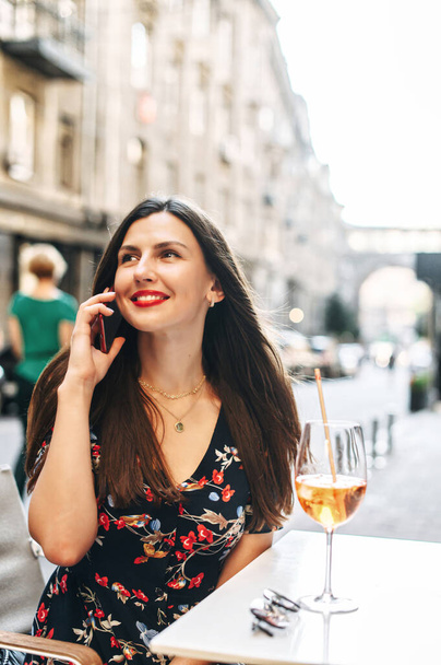 Belle fille parle sur un téléphone dans un café en plein air - Photo, image