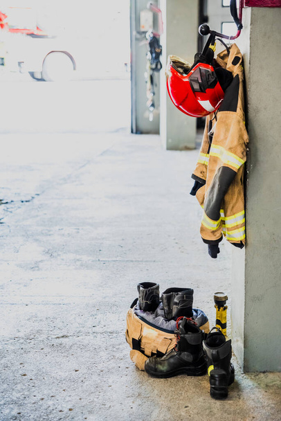 Csizma és tűzoltó dzseki egy tűzoltóállomás garázsában.. - Fotó, kép