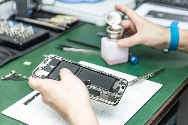 técnico irreconhecível reparar telefone inteligente em sua oficina de reparação
 - Foto, Imagem