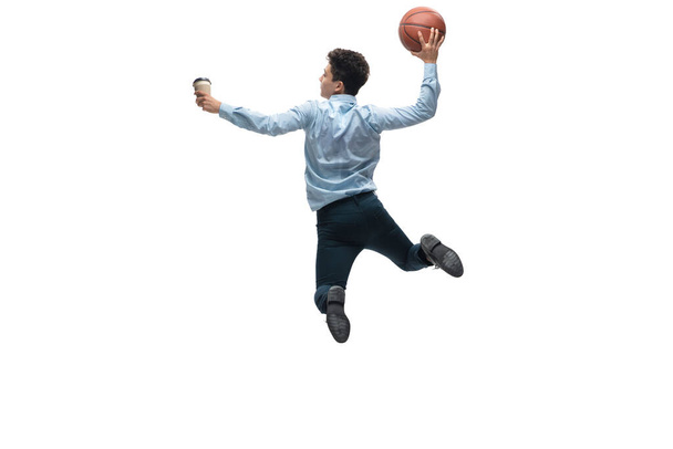 Ofis elbiseli bir adam beyaz arka planda basketbol oynuyor. Hareket halindeki bir iş adamı için alışılmadık bir görünüm. Spor, sağlıklı yaşam tarzı. - Fotoğraf, Görsel