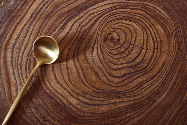Der goldene Löffel liegt auf einer Baumscheibe. Holztisch. Mit Kopierraum. Hochwertiges Foto - Foto, Bild