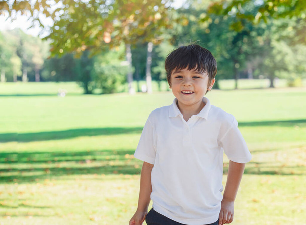 Portrait of happy school kid playing in the park, Child having fun playing outside in sunny day Autumn,  Little boy relaxing outdoor after school. Positive children concept - Photo, Image