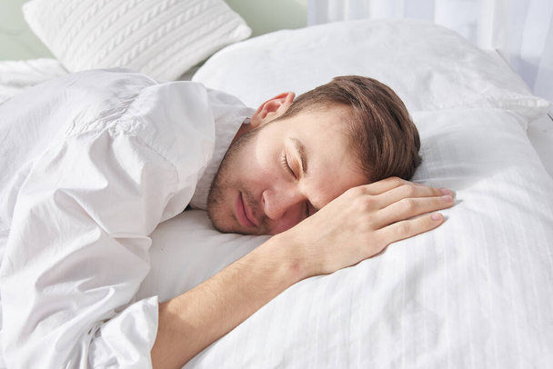 Close-up portrait of sleeping brunette man on white pillow - Zdjęcie, obraz