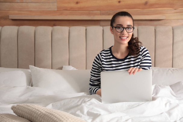 Young woman working with laptop on bed at home - Fotografie, Obrázek