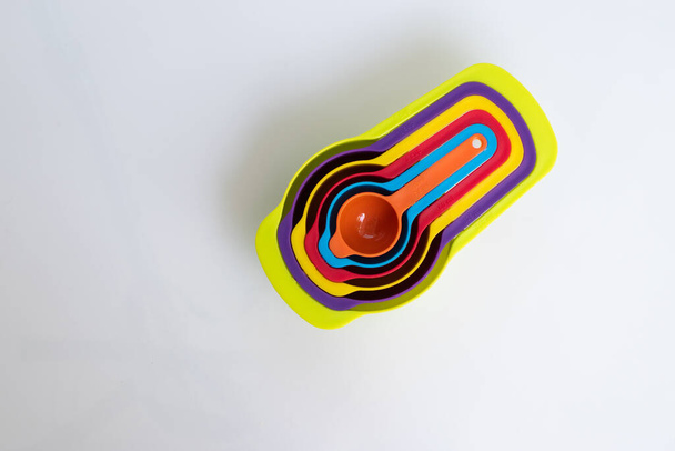 Ένα σετ από κουτάλια μέτρησης κατασκευασμένα από χρωματιστό πλαστικό. Ομάδα πλαστικών δοσομετρικών κουταλιών closeup, εξοπλισμός κουζίνας - Φωτογραφία, εικόνα