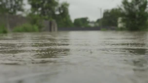 Überflutete Straße bei Überschwemmungen. Die Kamera steht auf dem Wasser. Wasser überflutete die Straße und den Zaun eines Privathauses. Es regnet und der Wasserspiegel steigt. Limnitsa-Fluss Ukraine. - Filmmaterial, Video