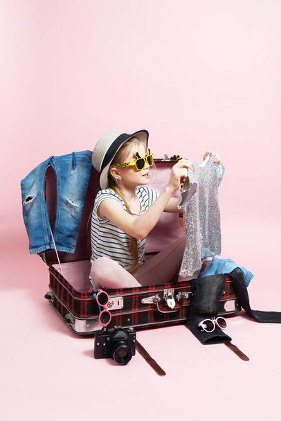 Travel: A schoolgirl girl prepares for a trip and collects clothes in a large suitcase. - Foto, Imagem