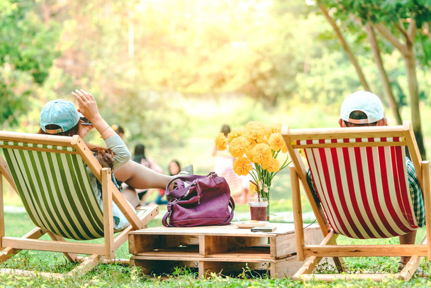 Зворотній бік щасливої жінки на літньому відпочинку, сидячи на садовому стільці, щоб розслабитися в громадському парку
. - Фото, зображення