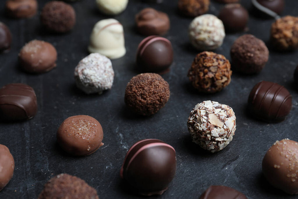 Different delicious chocolate candies on black table, closeup - Foto, afbeelding