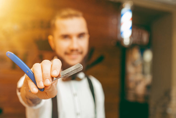 Young handsome bearded barber with a razor in his hand. Barber Shop - Foto, Bild