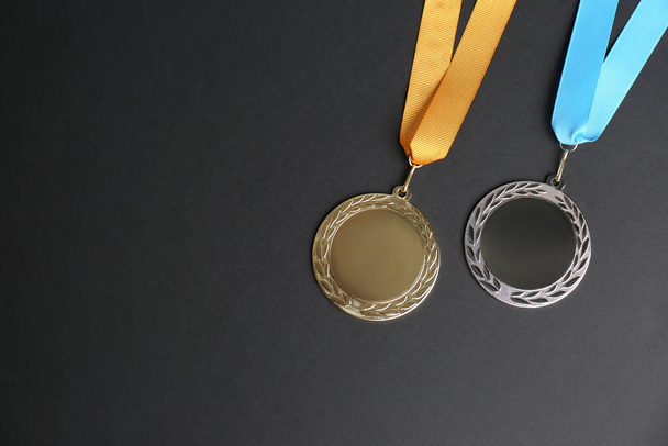 Gouden en zilveren medailles op zwarte achtergrond, vlakke lay. Ruimte voor ontwerp - Foto, afbeelding