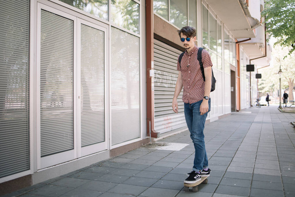 Attractive guy with sunglasses riding skateboard - 写真・画像