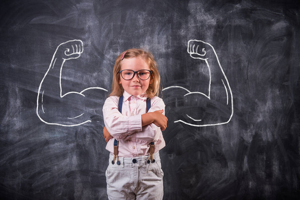 Funny school child showing muscles. Big and strong bicep concept for strength, confidence or defense from bullying. - Foto, imagen
