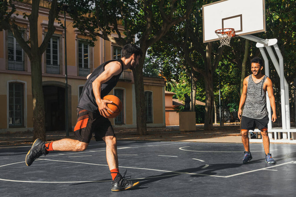 two young men play basketball outdoors - Foto, Imagem