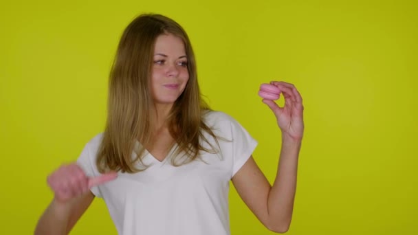 Frau hebt Hand mit rosa Makrone, zeigt Abneigung, schüttelt Hand und Kopf - Filmmaterial, Video