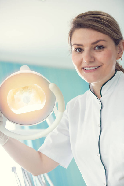 boldog fiatal női fogorvos eszközökkel orvosi háttér, fogászat és egészségügyi koncepció - Fotó, kép