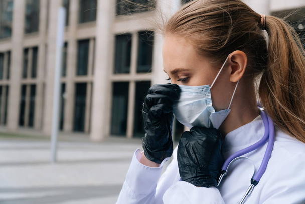 Eldivenle tıbbi maske takan genç bir kadın doktorun yüzünü yakından çek. Doktor konsepti insanı virüslerden korur. - Fotoğraf, Görsel